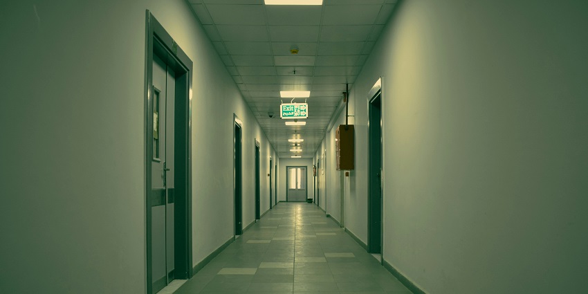 Long corridor with arched ceilings and dim lighting inside an old hospital building.