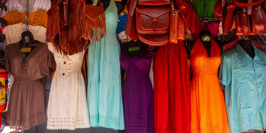 Bags and dresses are neatly arranged in a clothing stall at Vintage Market Dubai.
