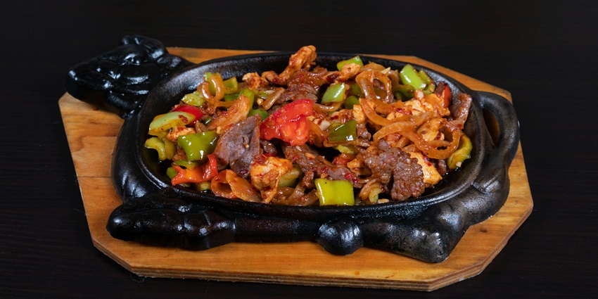 Sizzler served on a black dish with meat and vegetables in restaurants in Agartala.