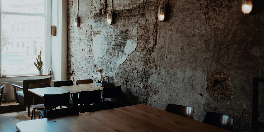 Industrial-style café with chalkboard menus, a barista at the counter, and hanging lights
