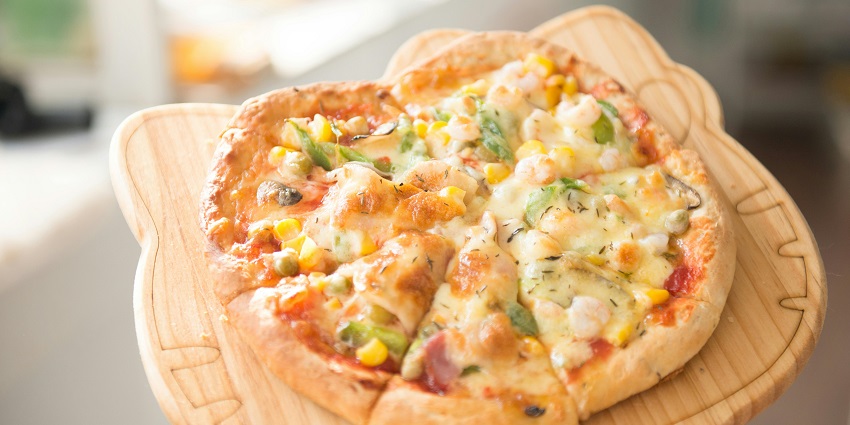 Freshly baked pizza served at 11th Avenue Café on a wooden table with a cosy ambience.
