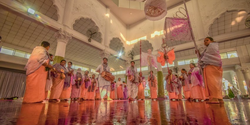 A group of performers dressed in colorful traditional attire dancing together in synchronized formation on stage.