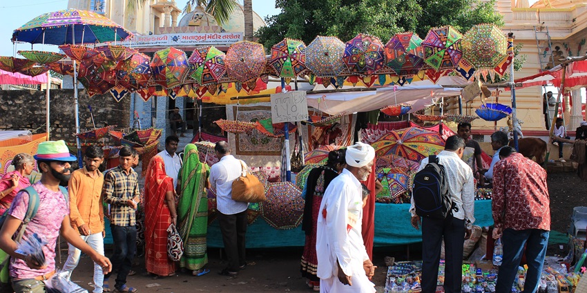 Image of a mela in Gujurat with vibrant stalls and people strolling around wearing traditional attire