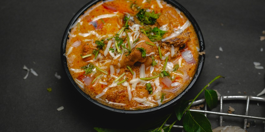 Chicken curry served in a bowl with spices and herbs at Ballygunge Cuisine.