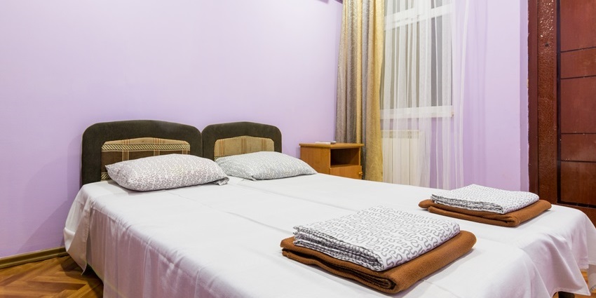 The interior of a small room of a budget hotel with a double bed, a window.