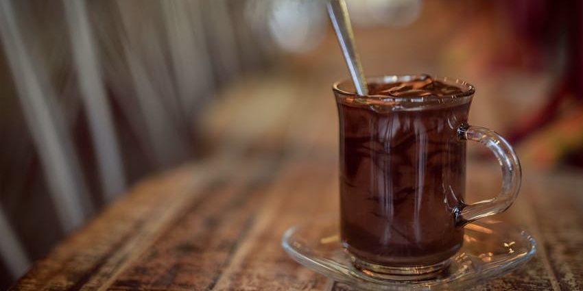 Hot chocolate served in a ceramic mug at a wooden table inside Cacao Bean Café.
