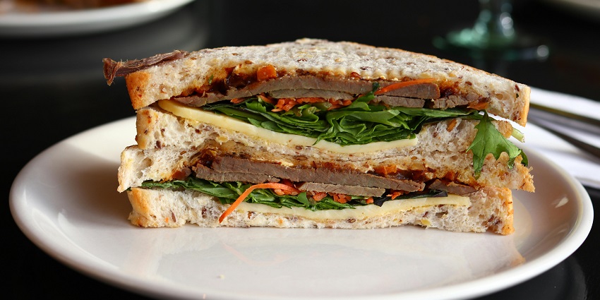 A chicken sandwich served on a white plate at Cafe Bellevue, one of the cafes in Uzan Bazar Guwahati.
