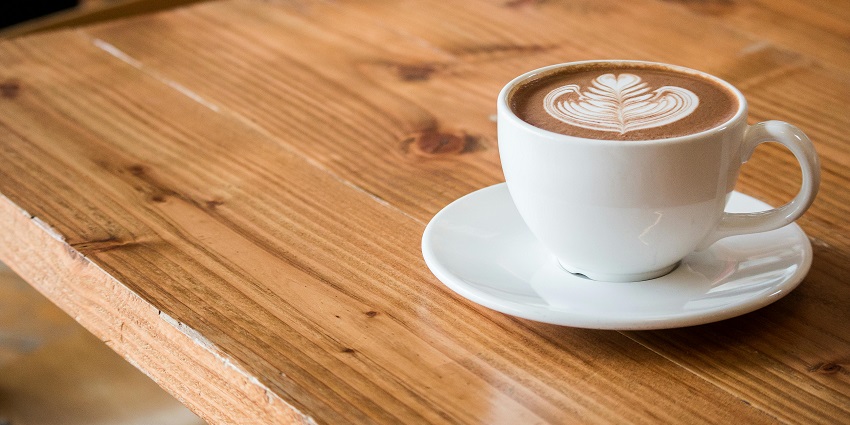 Cappuccino with latte art served at Café De Aroma in a ceramic cup.
