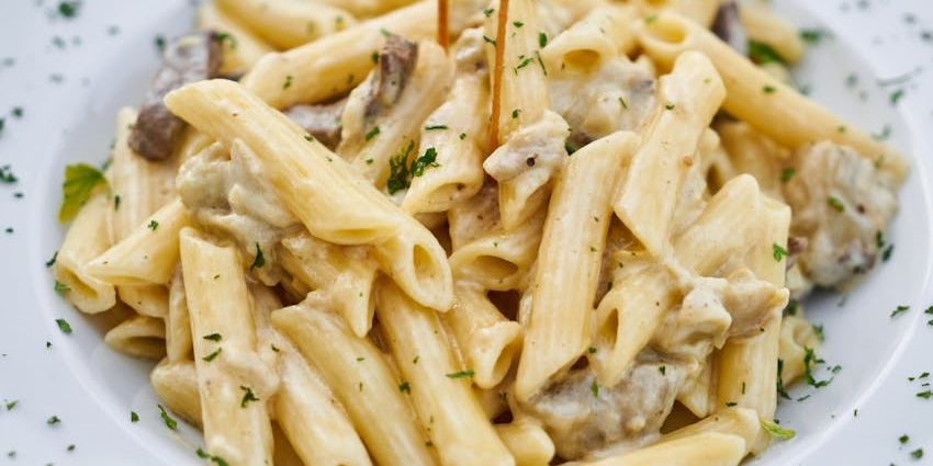 Creamy white sauce pasta served hot on a white plate at Cafe Royale.