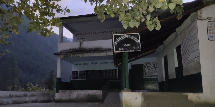 Evening view of a government school building in Chalal village, surrounded by forest hills
