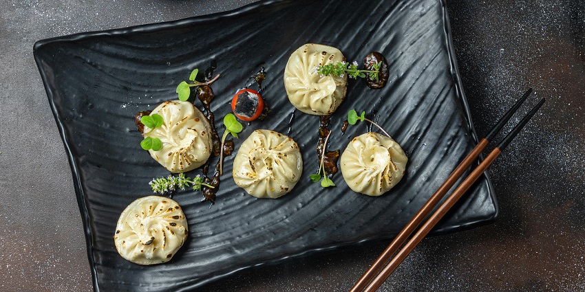Plate of steamed chicken momos served at a restaurant table.
