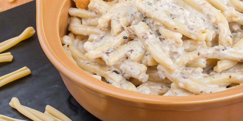 A creamy white sauce pasta with garlic bread sticks served hot at Craftery.