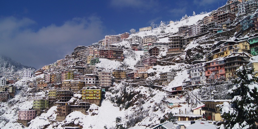 Snowfall in Shimla with snow-covered roofs and scenic hill landscape.