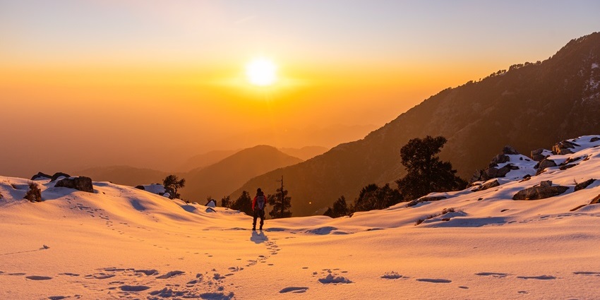 Golden sunset over Triund ridge with Dhauladhar peaks and valley below.