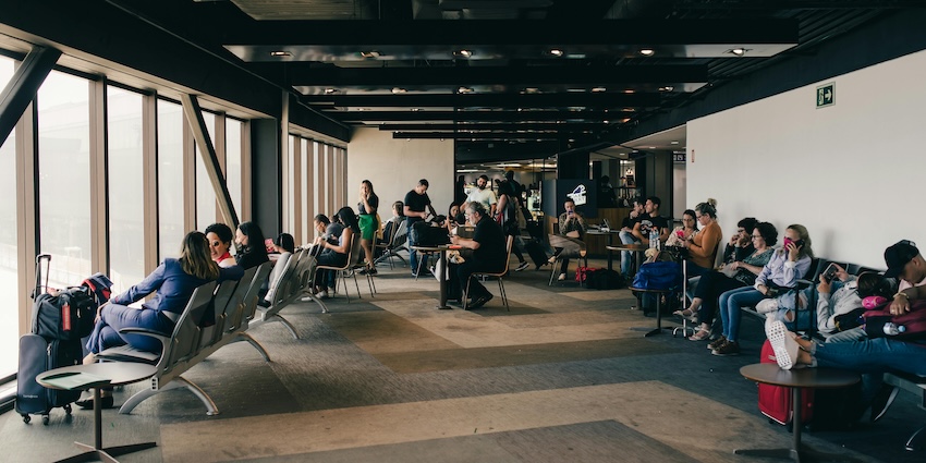 Passengers waiting inside an airport terminal lounge with seats, luggage, representing airports in Tripura.
