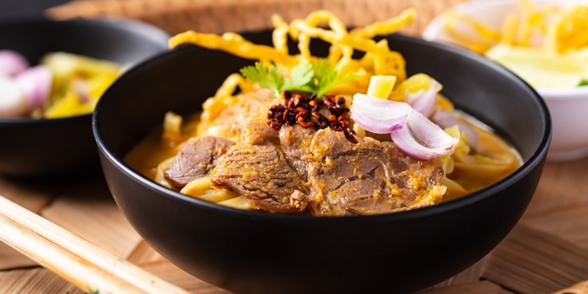 A bowl of traditional Thai khao soi is served at a local market food stall.