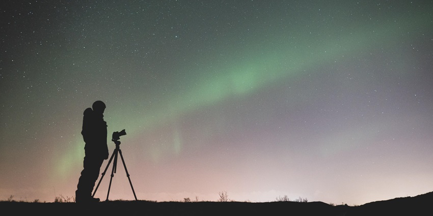 A photographer waiting to capture the perfect shot of the Northern Lights in Iceland.