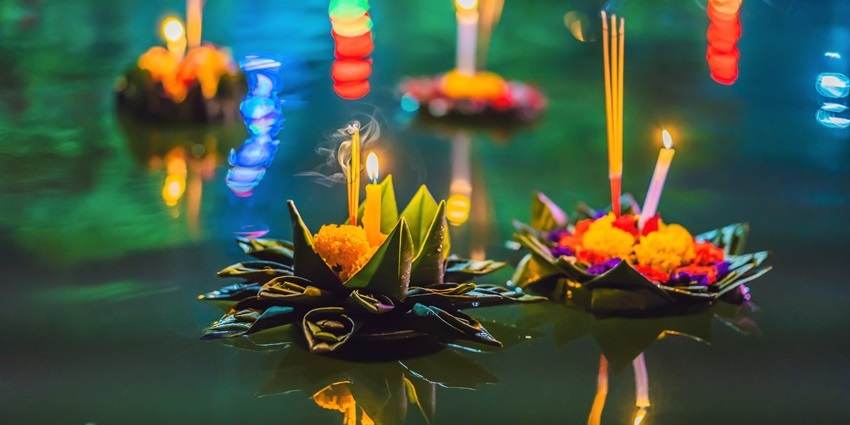 Close-up of a floating krathong decorated with flowers and candles on the Ping River during the Yi Peng Lantern Festival.