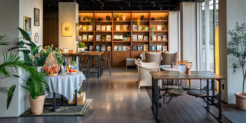 Interior of Forage Café featuring tables, chairs, and a wall-mounted bookshelf.
