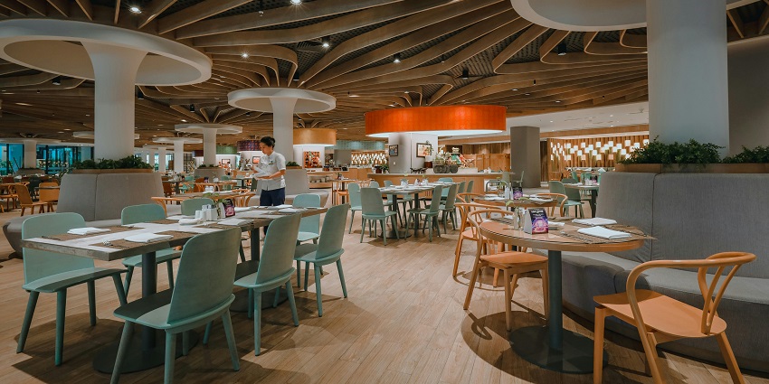 Gomoti restaurant with a modern ceiling design, wooden floors & arranged tables, one of the restaurants in Silchar.
