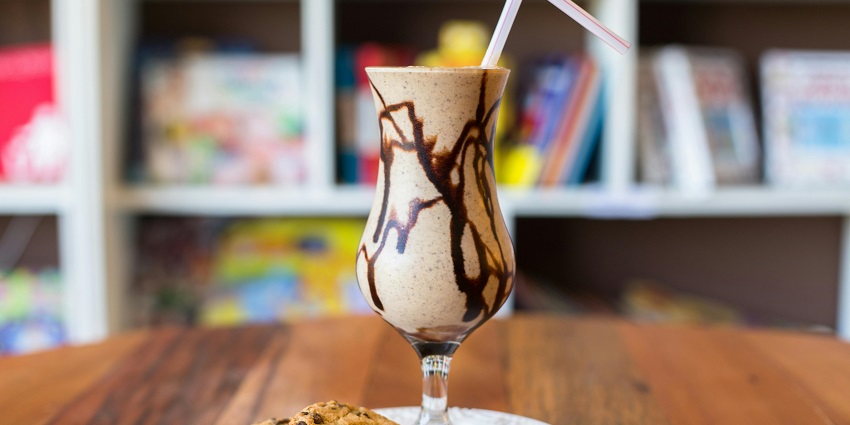Frappe served with a chocolate chip cookie at Good Day Cafe on a wooden table.
