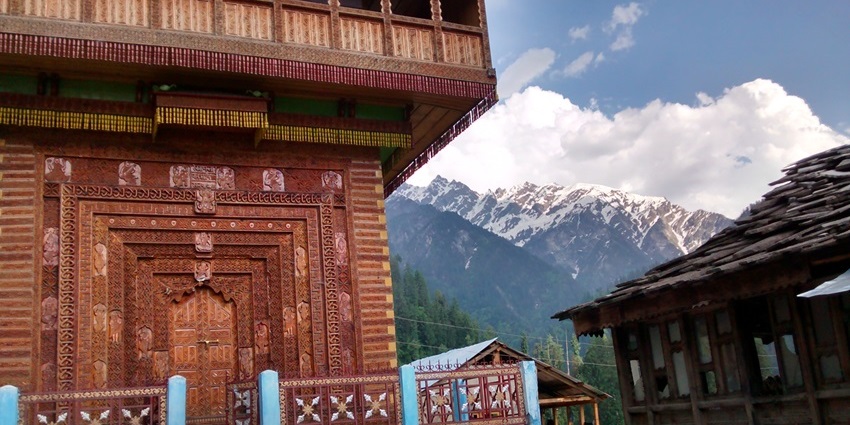 Wooden temple and houses in Grahan Village with snow-capped mountains in the background