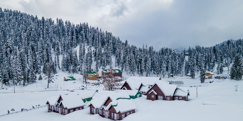 A spellbinding view of trees and houses in Gulmarg covered under a thick blanket of snow.
