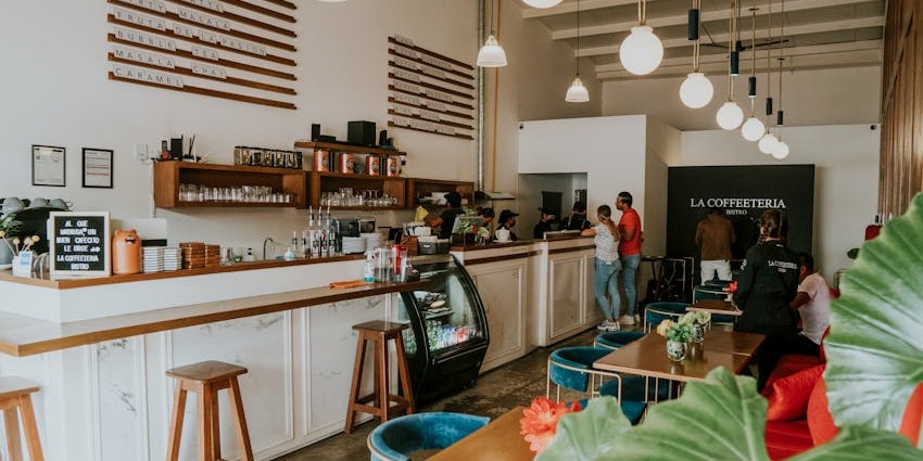 Bright café interior with white walls, hanging lights, wooden counters, and teal seating, one of the popular cafes in Darjeeling.