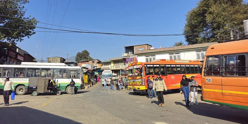Bhuntar bus station in Himachal Pradesh, with colourful buses and passengers under a clear sky