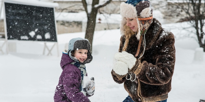 A child and an adult playing in the snow and making snowballs, showing snowfall in Srinagar.