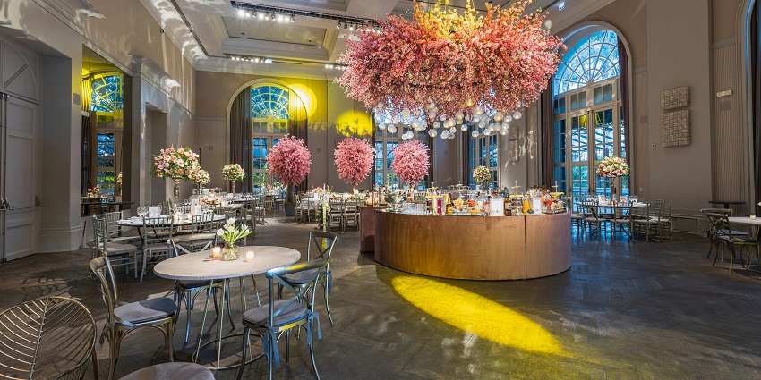 Grand banquet hall with cherry blossom décor, round tables, and elegant lighting.