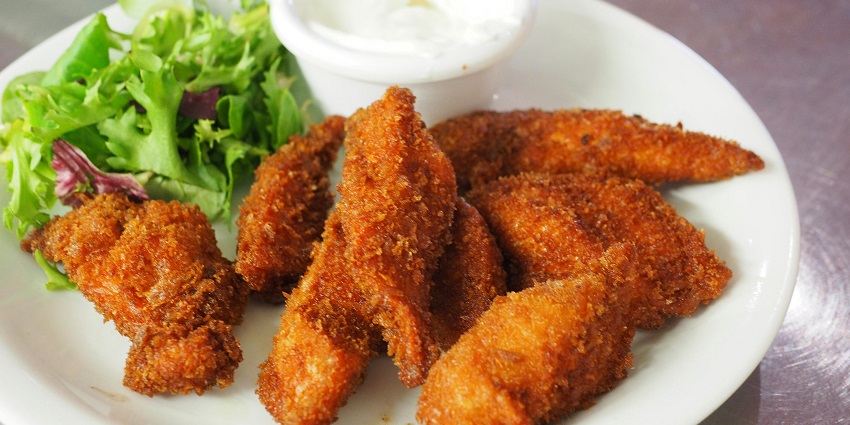 Crispy fried chicken strips served with fresh green salad and a side of dipping sauce.
