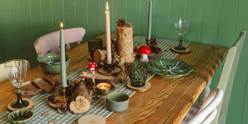 Rustic wooden table set with candles, pinecones, green crockery and woodland accents at Krishna Foods, one of the restaurants in Tezpur.
