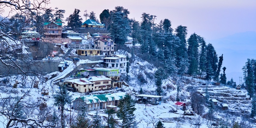 Kufri village landscape covered in snow with hills and trees during winter snowfall.