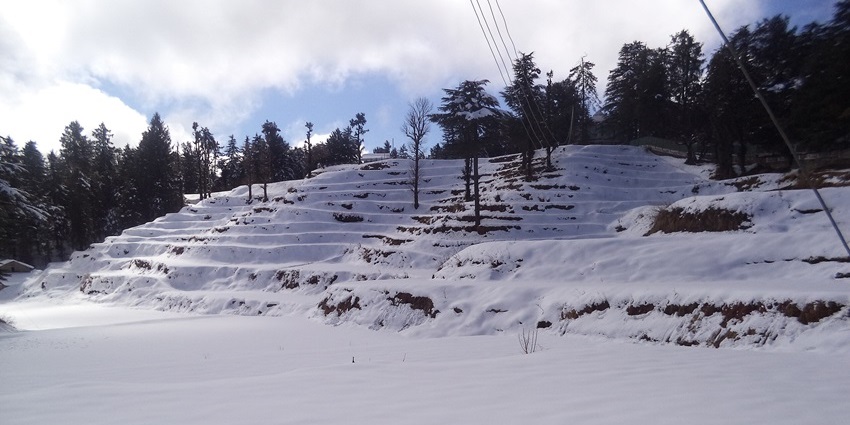 Picturesque Kullu Valley with snowy peaks and apple orchards during the winter season.