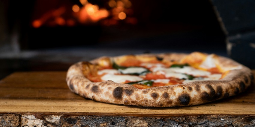 Wood-fired pizza served on a wooden tray at La Pino'z Pizza.
