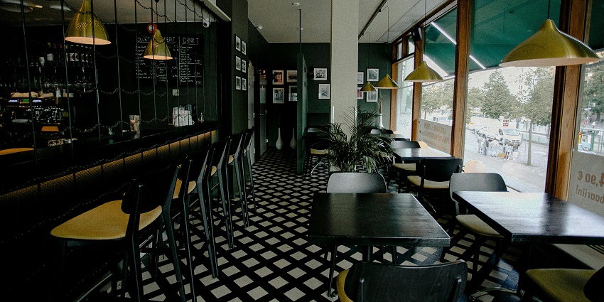 Modern restaurant with black tables, patterned floor, bar seating, and large windows, one of the restaurants in Shillong.
