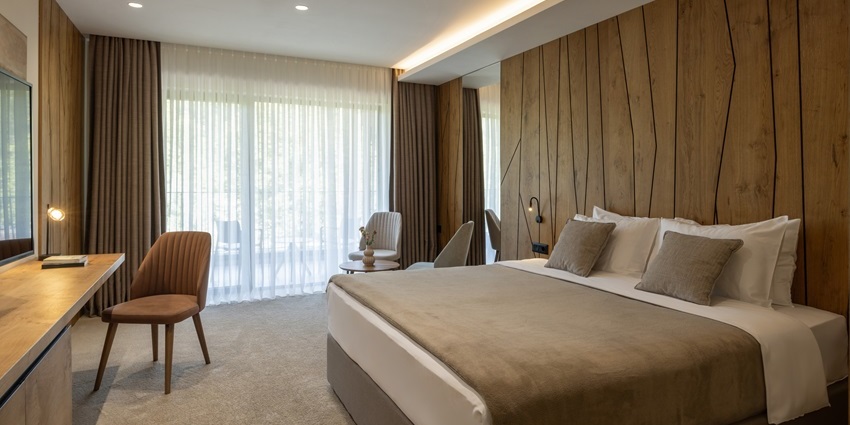 Modern hotel bedroom bathed in morning light, featuring a king-size bed and bedside tables