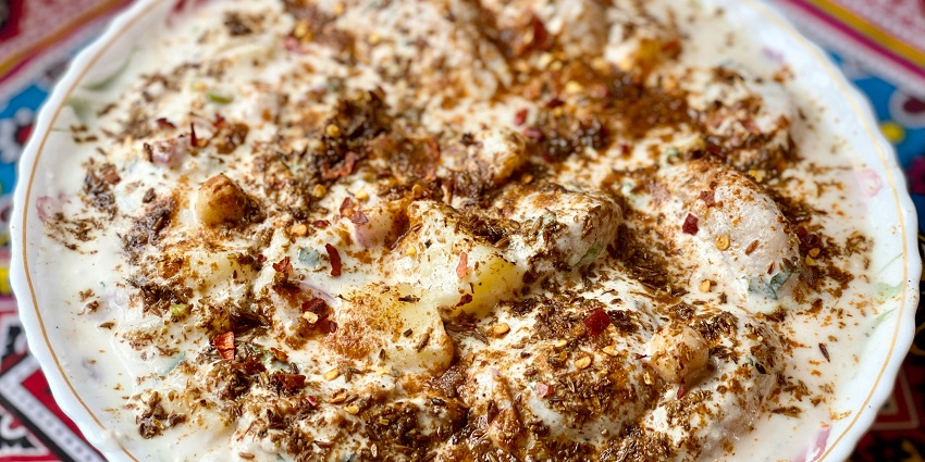 Plate of dahi vada topped with yogurt and chutneys, a popular Indian snack.
