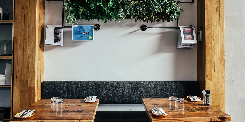Wooden café tables with glassware and cutlery, one of the charming restaurants in Tripura.