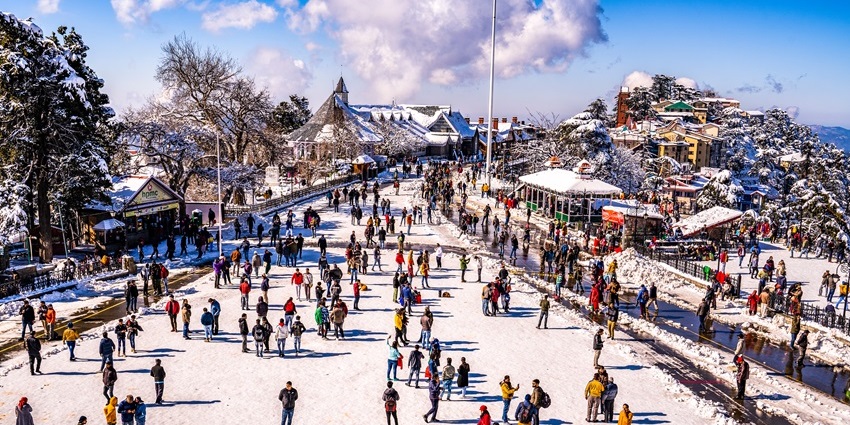 Mall Road in Shimla after snowfall with people walking along snow-covered street and shops.