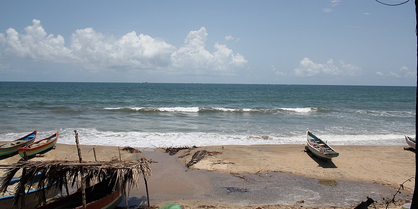 Serene view of Tarkarli Beach in Konkan, India, with fishing boats and blue sea waves.