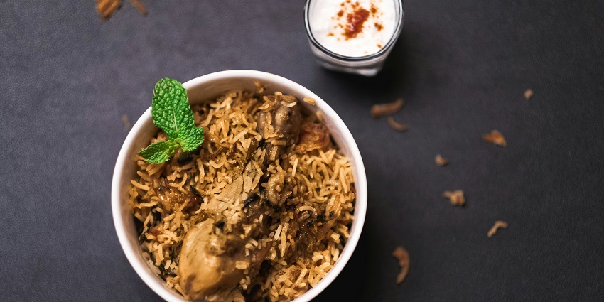 A close-up of a delicious chicken biryani with raita at Mughal Garden.