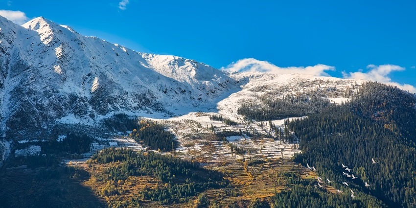 Aerial view of Narkanda with snow-covered Kailash Himalaya mountain slopes and forested hills.