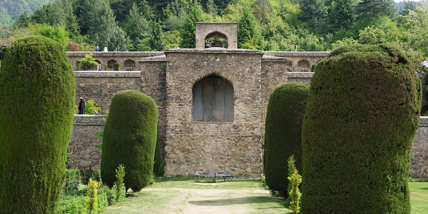 Old structure of Pari Mahal surrounded by green lawns and finely cut trees, showing snowfall in Srinagar.