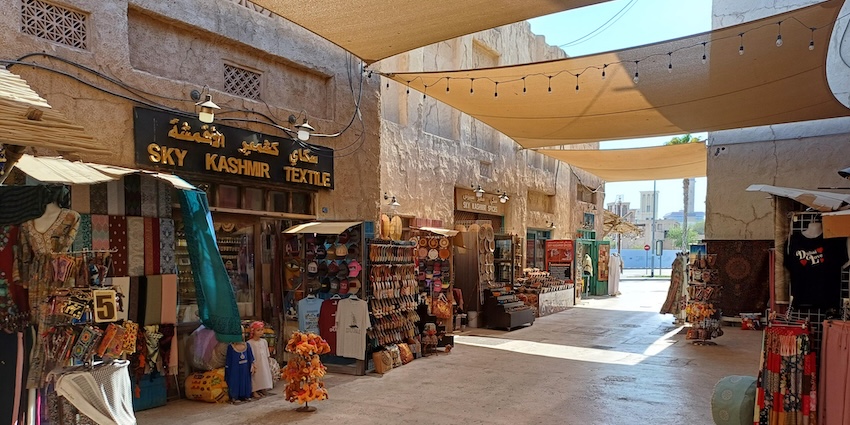 Narrow walkways lined on both sides with shops and stalls with goods hanging overhead.