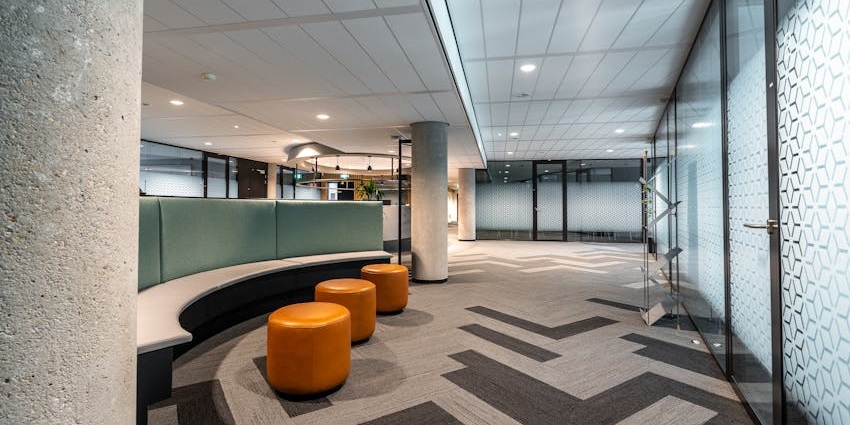 Airport waiting area with orange couches and seating, empty and well-lit interior space.