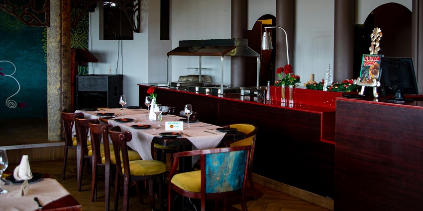Warmly lit restaurant interior with wooden chairs, table settings, and hanging lamps, one of the top restaurants in Aizawl.