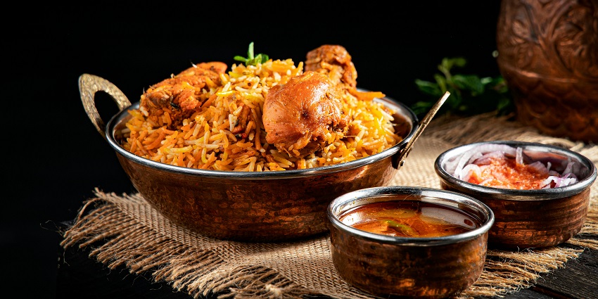 Clay pot filled with mutton biryani, served with curry, onions at the Roy’s Biryani Hub.
