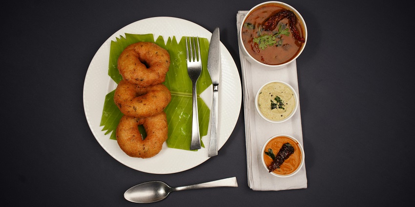 Crispy vada served on a plate with chutney at Sagar Ratna.
